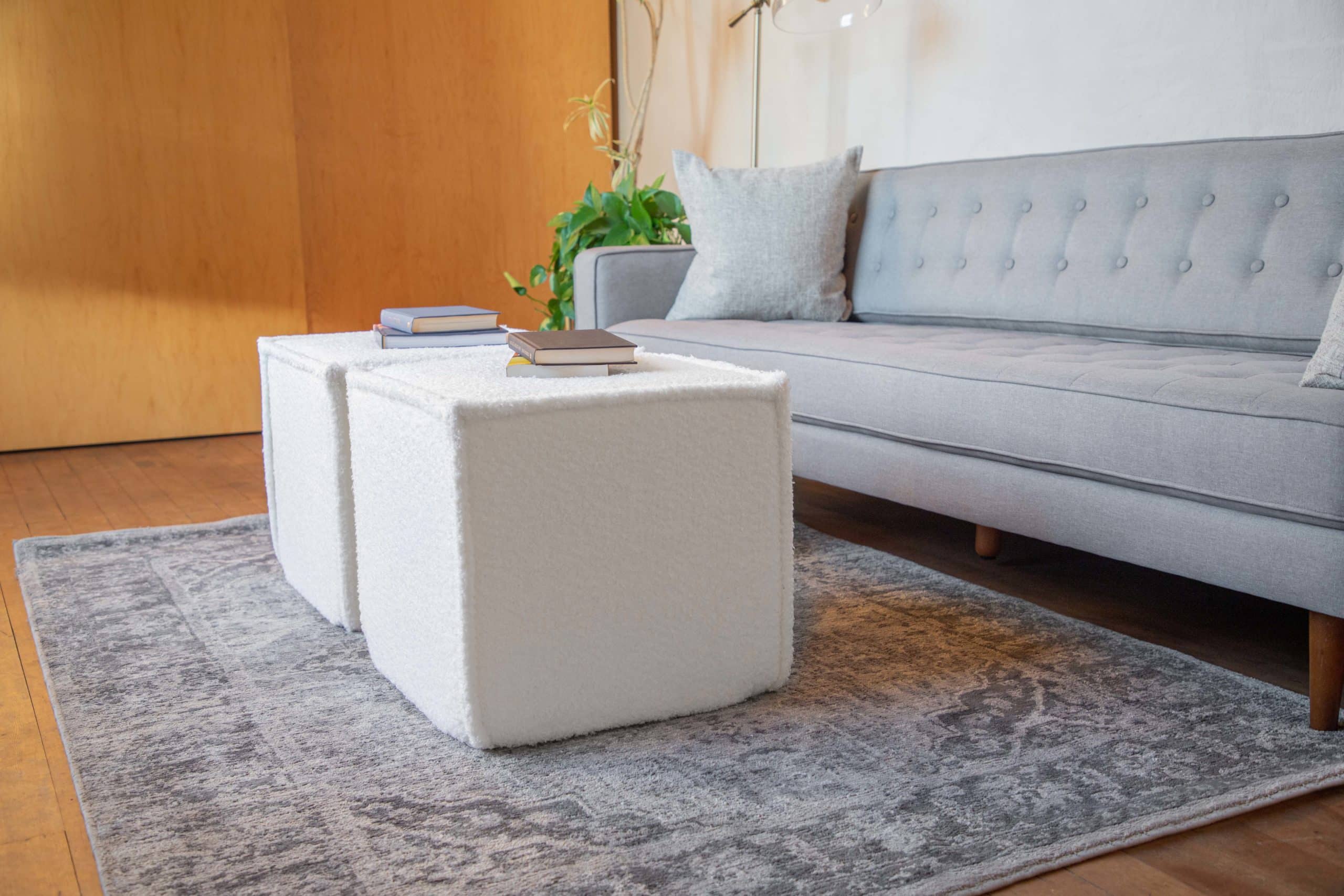 A modern living room features two Wovenbyrd square poufs with foam cores in cream faux fur.